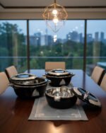 Stacked 3-piece black insulated hot pot set with chrome silver accents on a marble kitchen countertop.