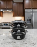 Stacked 3-piece black insulated hot pot set with chrome silver accents on a marble kitchen countertop.