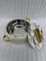 A professional studio shot of a set of three graduated-size insulated hotpots with gold handles, featuring a ribbed cream or grey body and decorative marble or wood-patterned lids, displayed on a kitchen countertop.