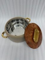 A professional studio shot of a set of three graduated-size insulated hotpots with gold handles, featuring a ribbed cream or grey body and decorative marble or wood-patterned lids, displayed on a kitchen countertop.