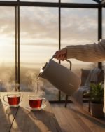 Feenik 2 liter thermal carafe vacuum flask displayed in Coffee, Grey, and White colors, featuring infographics highlighting the glass inside, airtight cap, sleek handle, push-button pouring, and sturdy plastic base.