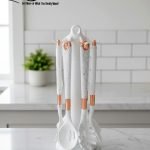 Luxury white marble-look cooking utensil set with rotating holder and rose gold accents. Includes spatula, spoon, and pasta server. Ideal kitchen decor centerpiece.