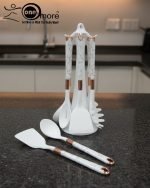 Luxury white marble-look cooking utensil set with rotating holder and rose gold accents. Includes spatula, spoon, and pasta server. Ideal kitchen decor centerpiece.