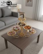 Luxurious gold tiered centerpiece serving stand with desserts and dry fruits on a coffee table. Ornate gold-plated serving tray for dry fruits and sweets. The Opulent Golden Tiered Serving Centerpiece