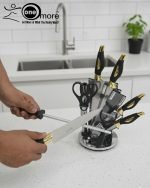 One More luxury 11-piece knife set in rotating stainless steel and clear acrylic block. Features black and gold accented handles, perfect as a modern kitchen centerpiece.