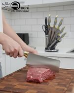 One More luxury 11-piece knife set in rotating stainless steel and clear acrylic block. Features black and gold accented handles, perfect as a modern kitchen centerpiece.