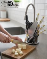 One More luxury 11-piece knife set in rotating stainless steel and clear acrylic block. Features black and gold accented handles, perfect as a modern kitchen centerpiece.