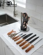 One More luxury 11-piece knife set in rotating stainless steel and clear acrylic block. Features black and gold accented handles, perfect as a modern kitchen centerpiece.