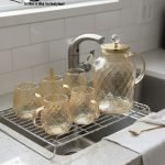 Full 7-piece amber glass water or tea set displayed on a wooden dining table with place mats and six matching cups.