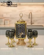 Fancy gold-tone beverage dispenser set with six matching stemmed goblets. The dispenser and glasses have a repeating geometric lattice pattern available in white and gold, blue and gold, or red and gold.