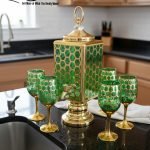Fancy gold-tone beverage dispenser set with six matching stemmed goblets. The dispenser and glasses have a repeating geometric lattice pattern available in white and gold, blue and gold, or red and gold.
