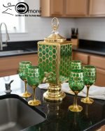 Fancy gold-tone beverage dispenser set with six matching stemmed goblets. The dispenser and glasses have a repeating geometric lattice pattern available in white and gold, blue and gold, or red and gold.