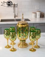 Luxury gold drink dispenser and goblet set with geometric pattern; available in two colors: royal blue/gold and emerald green/gold; featured on a modern kitchen counter.