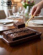 Luxurious golden cake knife and serving set with detailed palm leaf handles resting on a polished dark wood dining table, set for a formal dinner.