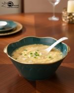 A complete 15-piece ceramic soup set displayed in a kitchen setting, featuring one large scalloped serving bowl, six small individual soup bowls, a golden metal storage stand, and seven white serving spoons. The set is available in six colors: black, dark gray-blue, navy blue, emerald green, beige/nude, and light mint green, all highlighted with an elegant gold rim.