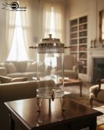 Luxury stainless steel and clear glass beverage dispenser with ornate gold-tone base and handles, available in 7-liter and 10-liter sizes, shown serving infused water at an elegant event.