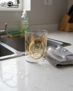 Decorative acrylic storage jar with a clear body and elegant gold spiral print, suitable for use as a kitchen canister, snack container, or display piece on a coffee table or serving cart.