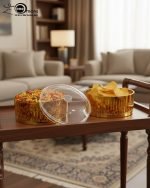 Close-up of a luxury two-tier gold fluted acrylic dish filled with green grapes and cherries, placed on a white table runner on a wooden dining table.