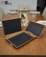 Set of three nesting fiber serving trays with non-slip textured surfaces and cut-out handles, displayed on a wooden dining table. The available colors are black, dark brown, grey, off-white, and rust-brown.
