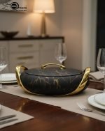 A set of three stacked white marble-patterned insulated casserole dishes (hot pots) with striking gold-tone handles and lids, displayed on a formal dining table.