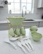 A complete 15-piece ceramic soup set displayed in a kitchen setting, featuring one large scalloped serving bowl, six small individual soup bowls, a golden metal storage stand, and seven white serving spoons. The set is available in six colors: black, dark gray-blue, navy blue, emerald green, beige/nude, and light mint green, all highlighted with an elegant gold rim.