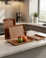 Set of three nesting fiber serving trays with non-slip textured surfaces and cut-out handles, displayed on a wooden dining table. The available colors are black, dark brown, grey, off-white, and rust-brown.