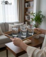 Set of three nesting fiber serving trays with non-slip textured surfaces and cut-out handles, displayed on a wooden dining table. The available colors are black, dark brown, grey, off-white, and rust-brown.