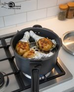 One More non-stick pressure cooker used as a steamer for three seasoned chicken drumsticks wrapped in foil on a metal rack.