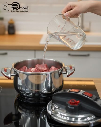 Top-down view of the O.M.S. Callacook 5-Litre Turkish pressure cooker lid. The lid features a sleek stainless steel and black plastic housing with two prominent red push buttons for the unique, easy-to-use locking and unlocking mechanism. A separate red lever near the edge controls the advanced pressure valve, highlighting the high-quality, modern design and superior safety features of this premium, imported Turkish cooker.