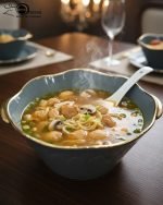 A complete 15-piece ceramic soup set displayed in a kitchen setting, featuring one large scalloped serving bowl, six small individual soup bowls, a golden metal storage stand, and seven white serving spoons. The set is available in six colors: black, dark gray-blue, navy blue, emerald green, beige/nude, and light mint green, all highlighted with an elegant gold rim.