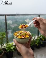 A complete 15-piece ceramic soup set displayed in a kitchen setting, featuring one large scalloped serving bowl, six small individual soup bowls, a golden metal storage stand, and seven white serving spoons. The set is available in six colors: black, dark gray-blue, navy blue, emerald green, beige/nude, and light mint green, all highlighted with an elegant gold rim.