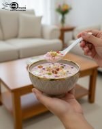 A complete 15-piece ceramic soup set displayed in a kitchen setting, featuring one large scalloped serving bowl, six small individual soup bowls, a golden metal storage stand, and seven white serving spoons. The set is available in six colors: black, dark gray-blue, navy blue, emerald green, beige/nude, and light mint green, all highlighted with an elegant gold rim.