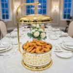 Royal gold and silver chafing dish for buffet service, featuring an ornate laser-cut pattern and a high gold stand with a hinged lid. Available in 4 and 6 liter capacities, designed for catering, weddings, and high-end events to keep foods like biryani, curry, or fried shrimp warm.