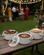 A stacked set of three premium insulated hot pots (1L, 2L, 3.5L) in a crisp white color with decorative gold-toned handles, shown on a marble kitchen countertop. The set features clear acrylic lids and is marketed for keeping food warm.