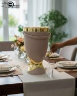 Insulated, stylish beverage dispenser (water cooler) with gold accents on base and spigot, shown in white, green, and chocolate/taupe colors, used for serving drinks on a dining table or kitchen counter.