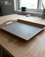 Set of three nesting fiber serving trays with non-slip textured surfaces and cut-out handles, displayed on a wooden dining table. The available colors are black, dark brown, grey, off-white, and rust-brown.