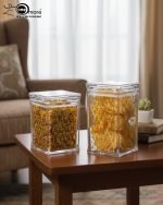 Clear acrylic storage jars with a subtle geometric pattern, shown holding snacks on a wooden table in a living room setting. Set of two sizes.