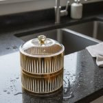 Close-up of a luxury two-tier gold fluted acrylic dish filled with green grapes and cherries, placed on a white table runner on a wooden dining table.