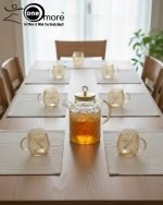 Full 7-piece amber glass water or tea set displayed on a wooden dining table with place mats and six matching cups.