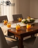 Full 7-piece amber glass water or tea set displayed on a wooden dining table with place mats and six matching cups.