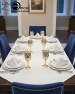 Fancy gold-tone beverage dispenser set with six matching stemmed goblets. The dispenser and glasses have a repeating geometric lattice pattern available in white and gold, blue and gold, or red and gold.