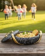A set of three stacked white marble-patterned insulated casserole dishes (hot pots) with striking gold-tone handles and lids, displayed on a formal dining table.