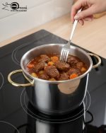 Stainless steel 6-liter pressure cooker with elegant gold handles and black safety locking lid, releasing steam on a stovetop, filled with beef stew – FALEZ kitchenware collection.