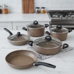 Falez 9-piece brown speckled granite non-stick cookware set displayed on a kitchen counter, featuring a fry pan, shallow casserole, and three deep pots with glass lids - Made in Turkey.