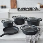 Falez 9-piece black granite non-stick cookware set including deep pots, shallow casserole, and fry pan with glass lids, displayed on a marble kitchen countertop.
