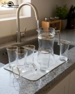 Pasabahce 7-piece Turkish glass water set featuring a textured finish and gold rims, consisting of one jug and six glasses, displayed on a kitchen counter by Onemore Crockery.