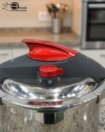 O.M.S/ONEMORE 14-liter stainless steel pressure cooker with red handles sitting on a kitchen stovetop, featuring an open lid with steaming hot meat stew inside.