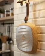 Falez square granite non-stick grill pan cooking grilled chicken breast and vegetables with perfect char marks, featuring a beige speckled finish and ergonomic brown handle.