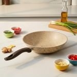Falez beige granite non-stick wok pan made in Turkey, displayed on a marble kitchen counter with fresh ingredients, showing dynamic stir-fry cooking with shrimp and easy cleaning with a white cloth.