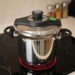 Falez 7-liter stainless steel pressure cooker made in Turkey sitting on a black stovetop, showing steam venting and food cooking inside, available at ONEMORE.